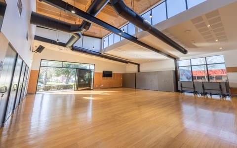 Large open hall with timber floor, exposed duct services, and coloured glazed panels