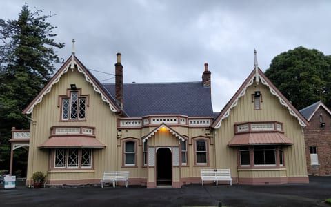 Ornate historic house with gabled roof, windows, and manicured grounds