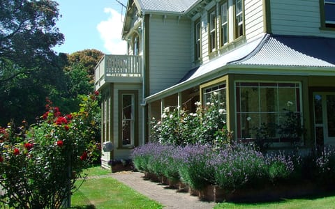 Two-storey villa exterior with a verandah, lavender garden border and mature trees
