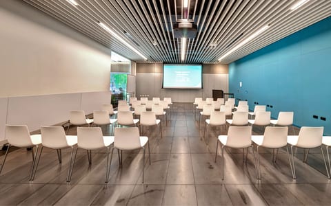 Conference room with white chairs in theatre layout and projected screen
