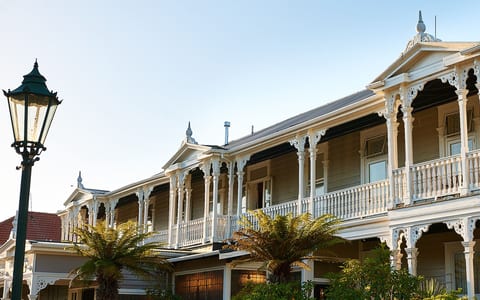 White two-storey Victorian-era hotel with ornate lacework verandahs, columns and decorative parapets