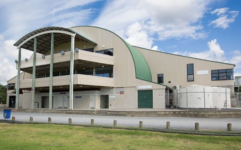 Two-storey arched metal roof building exterior with lawn in foreground