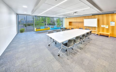 Meeting room with long table, chairs, whiteboard and timber wall panels