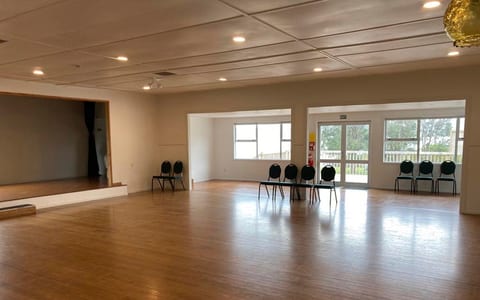 Empty community hall with timber floor, raised platform and windows