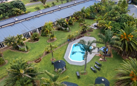 Aerial view of resort buildings, lawn, pool, and tropical plantings