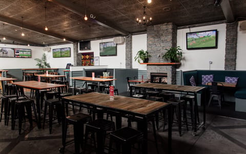 Outdoor courtyard with metal chairs and tables under pergola, venue signage on wall