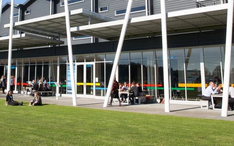 Modern events centre exterior with white colonnade and lawn area with attendees