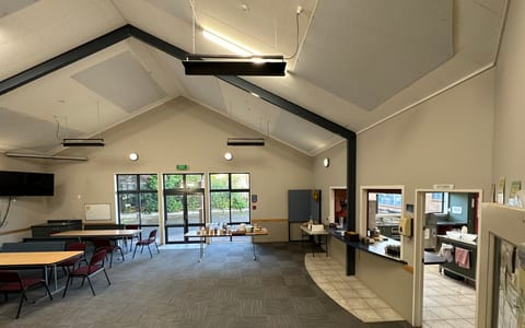 Vaulted community hall with tables, chairs and pass-through kitchen window