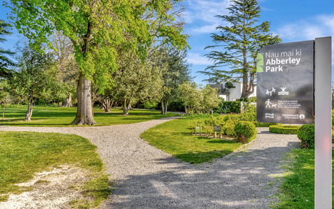 Park entrance with gravel path, park signage, and lawns