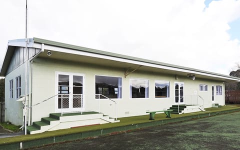 Single-storey hall building with green roof, verandah and outdoor steps