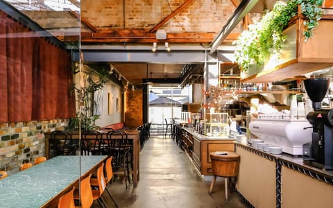 Industrial cafe interior with exposed brick, concrete floor, hanging plants, bar counter and seating