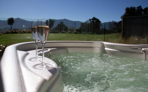 Outdoor spa pool with two champagne glasses on the edge and mountain views