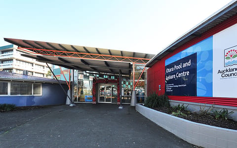 Red and blue painted building exterior with covered entrance canopy, carpark setting