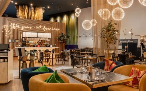 Contemporary hotel bar and restaurant with spherical pendant lights, timber slat screens, and coloured seating