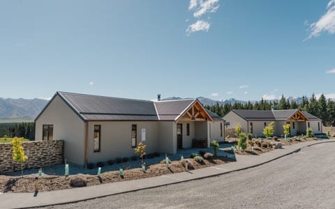 Cream render cottages with dark metal roofs and timber porch gables, mountain range behind