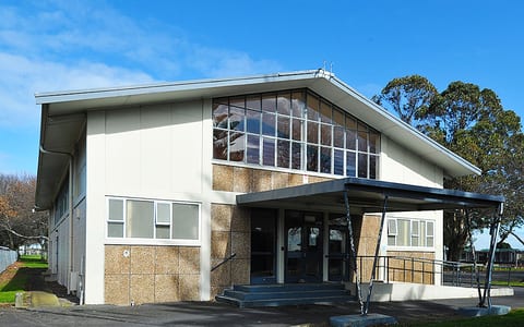 Two-storey community hall exterior with wide glazing and aggregate cladding