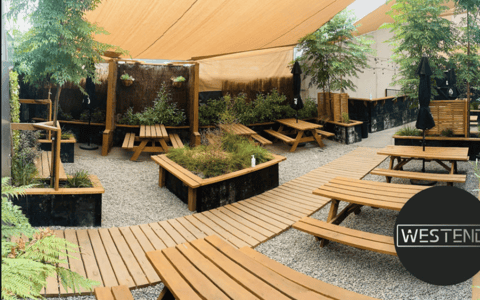Outdoor beer garden with timber benches, raised planting beds and shade sails