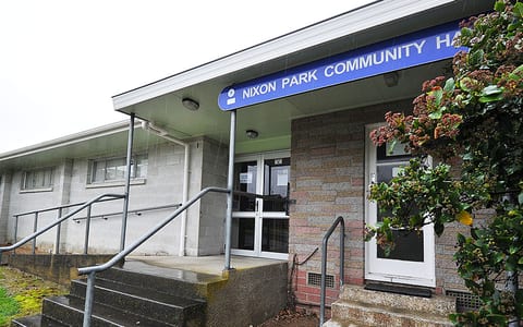 Community hall exterior with brick entrance, signage and glazed door in rain