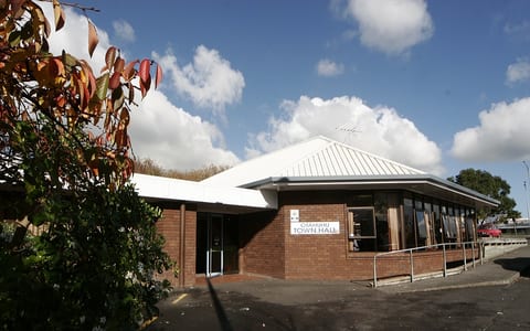 Single-storey brick community hall with white pitched roof and entry sign