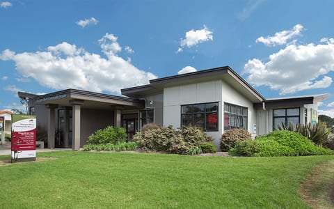Single-storey community building with flat roof, large windows, and lawn in front