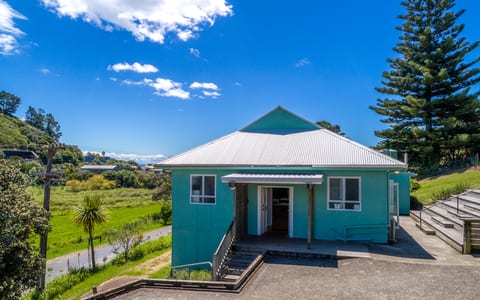 Aerial view of small teal-painted hall with corrugated iron roof on grassy site