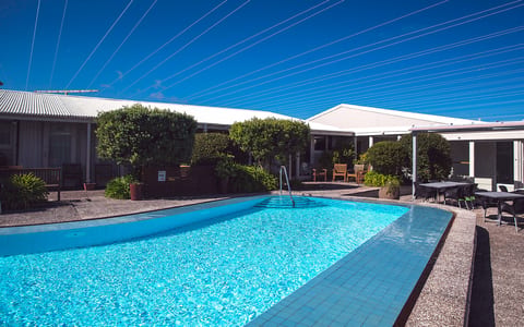 Outdoor swimming pool with garden and motel buildings surrounding it