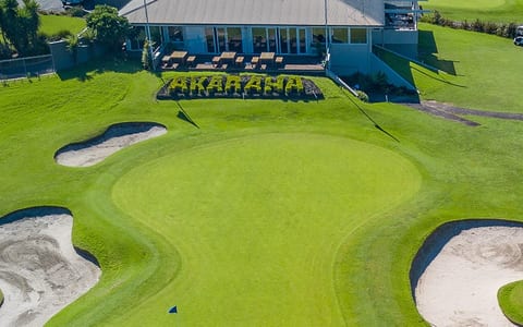 Aerial view of Akarana Golf Club clubhouse and course with sand bunkers and a topiary hedge spelling the club name