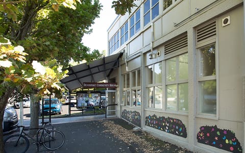 Community house exterior with entrance canopy, bikes and decorative window murals