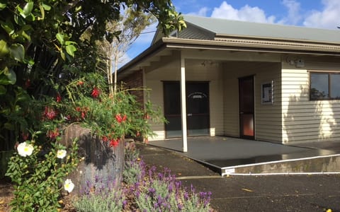 Cream weatherboard hall with covered entry porch, mixed garden planting in foreground