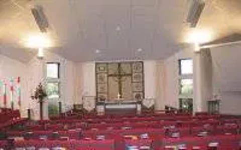 Small church auditorium with red upholstered pews and altar area