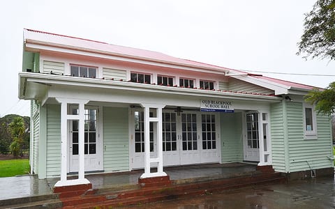 White timber hall with covered veranda, French doors, and red iron roof, wet forecourt
