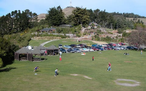Open park area with lawn, pavilion shelters and hillside in background