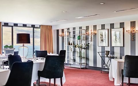 Restaurant dining room with striped feature wall, round tables and lake view through window