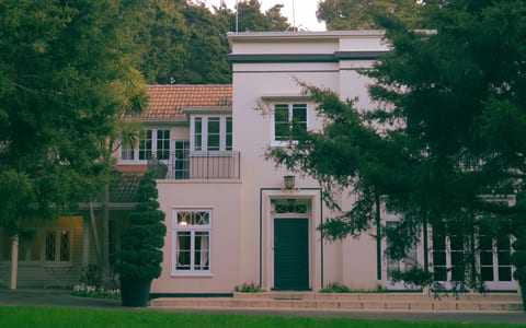 Two-storey rendered manor house with terracotta roof set among mature trees