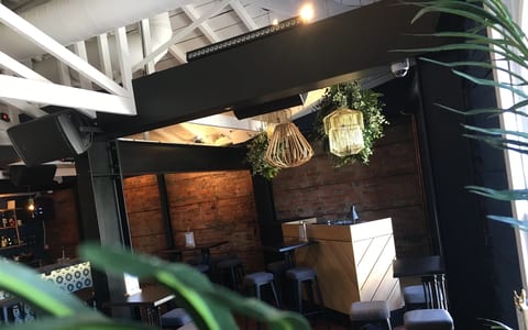 Dark industrial interior with exposed brick wall, hanging pendant lights, and bar stools
