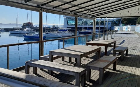Timber deck overlooking a marina with long timber benches, boats moored at calm waterfront