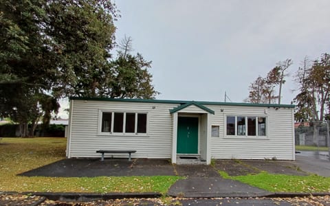 Small white weatherboard hall with green roof and entry door