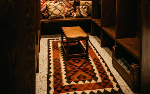 Dark timber-panelled lounge nook with a gilt mirror, kilim rug and built-in bench seating