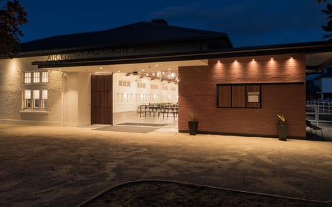 Low single-storey venue exterior lit at night with open doors revealing a set room