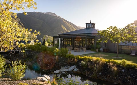 Pavilion building with pond, garden and mountain backdrop at sunset