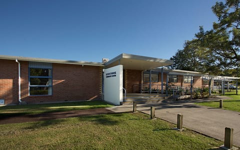 Low-rise brick community centre building with covered entrance and lawn