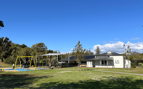 Modern white community centre building with park and playground beside