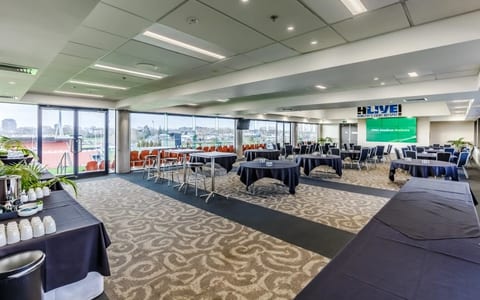 Stadium lounge set up for a conference with round tables and a large screen