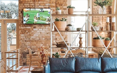 Pub interior with exposed brick, patterned floor tiles, blue sofa and shelving