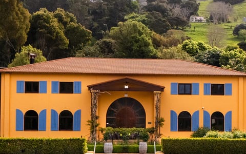 Two-storey ochre winery building with blue shutters and arched entrance