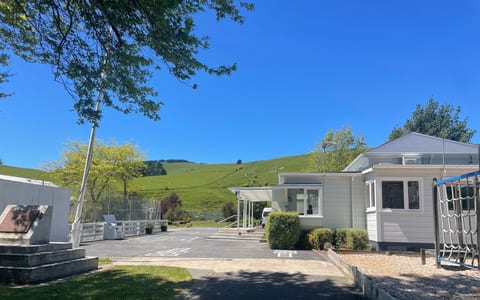 White hall building with playground and rolling green hills behind