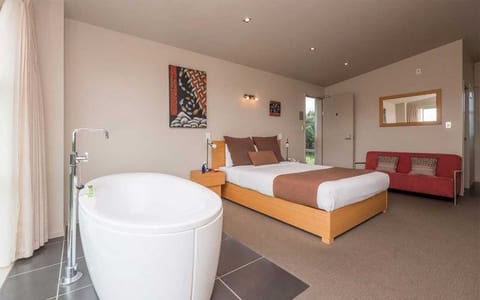 Suite with a freestanding bath, king bed and garden outlook through sliding doors