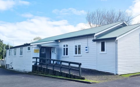 White weatherboard community hall exterior with green roof