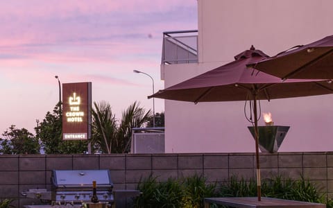 Rooftop terrace at dusk with timber tables, market umbrella, gas torch, garden strip