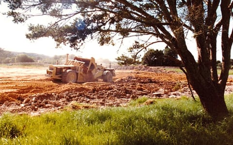 Earthworks and grading of sports grounds with trees and machinery